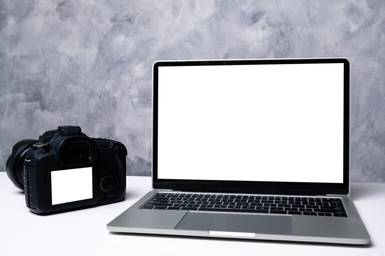 A black digital camera and a computer laptop on a table